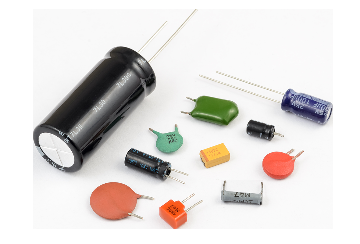 Figure 154: Various capacitor types shown together — electrolytic (large black cylinder), ceramic disc, film, tantalum, and others in different shapes and sizes