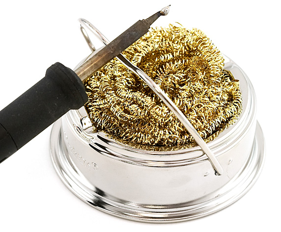 Soldering iron tip being cleaned in brass sponge
